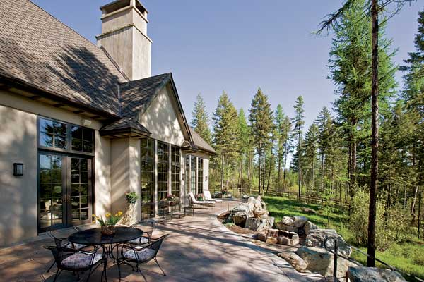 The home offers plenty of outdoor living space to appreciate the site's evergreens and Aspen trees. The terrace on this side of the home has stairs that lead down to a landscaped lawn.